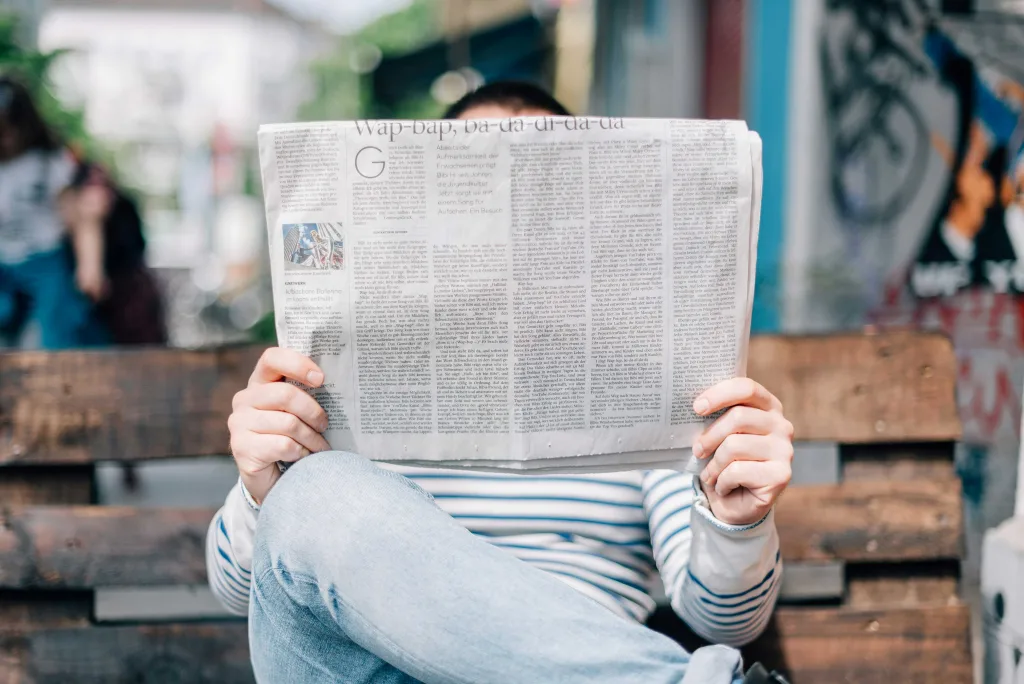 Photo d'un homme en marinière assis sur un banc lisant le journal