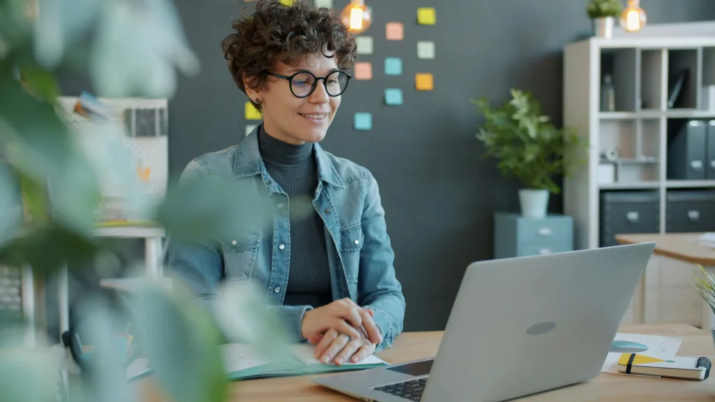 Photo d'une femme aux cheveux courts qui sourri devant un pc